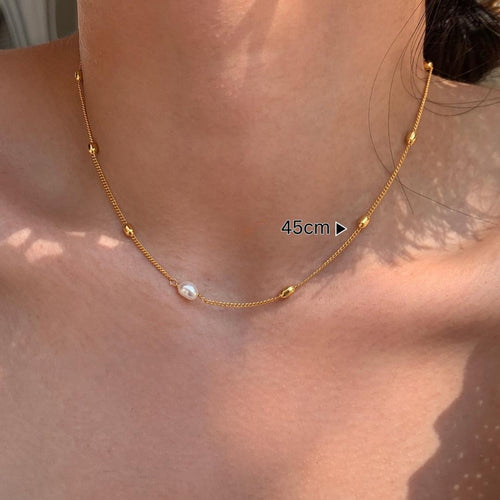 Gold necklace with a pearl pendant on a person's neck, labeled 45cm.